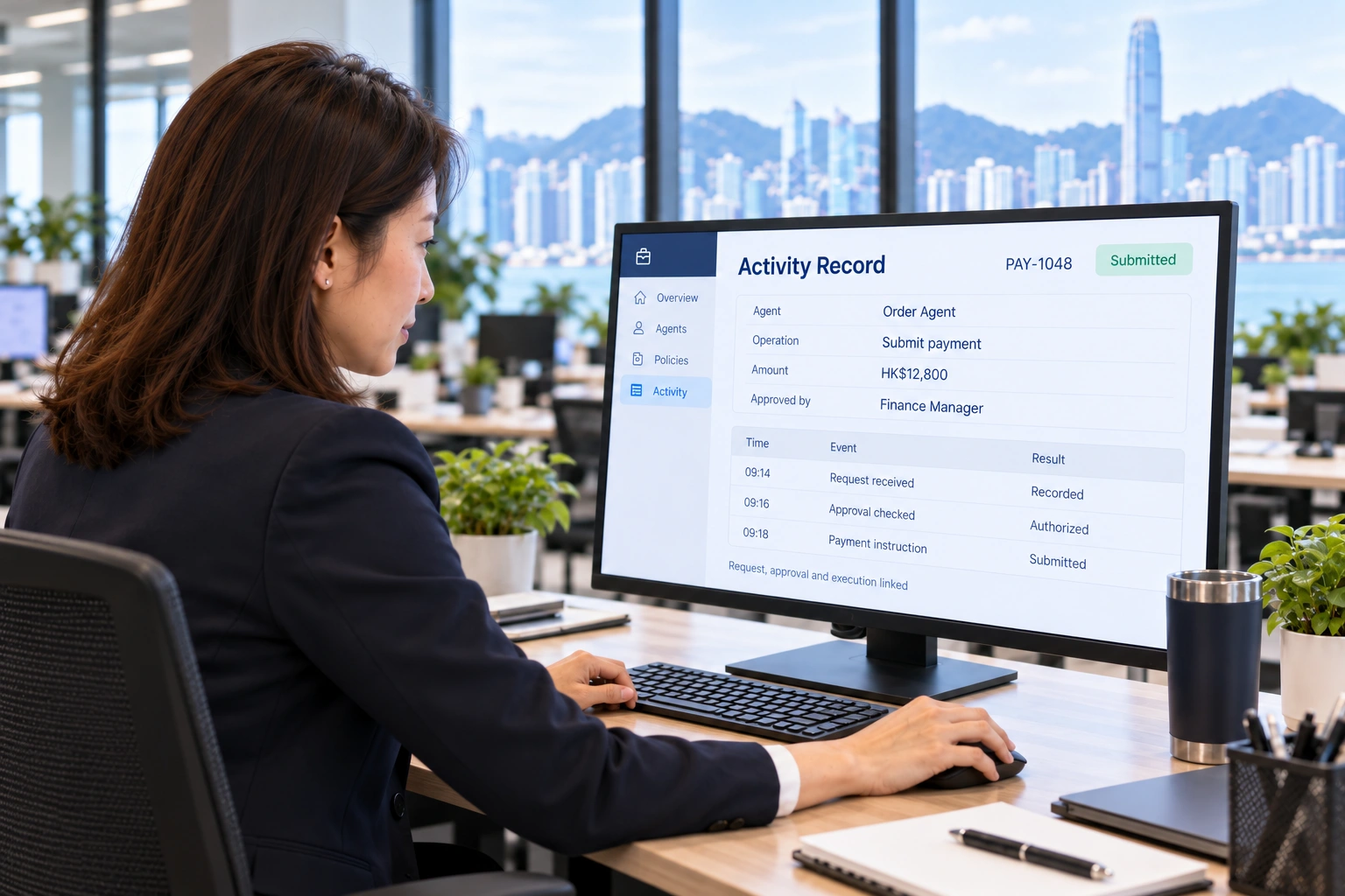 Viewed from behind and to the side, the manager reviews a detailed Activity Record on a large monitor facing her, with her right hand on the mouse